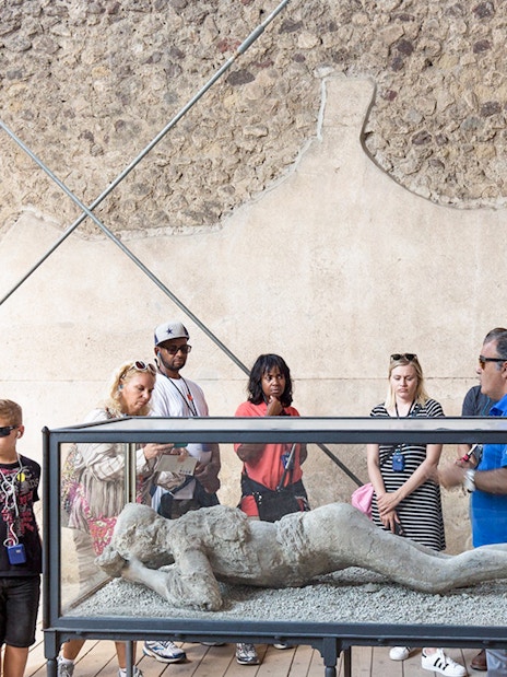 Tour guide explaining Pompeii victim cast to tourists.