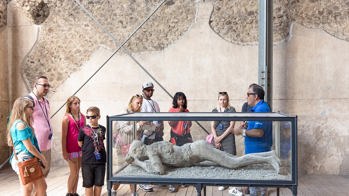 Tour guide explaining Pompeii victim cast to tourists.
