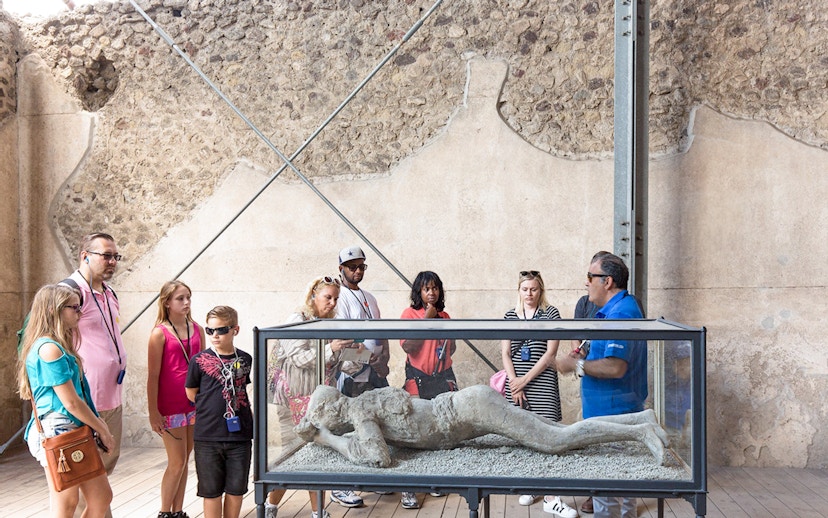 Tour guide explaining Pompeii victim cast to tourists.