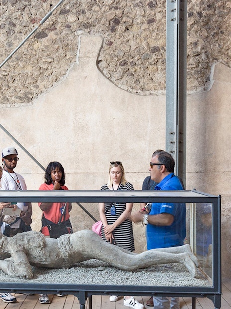 Tour guide explaining Pompeii victim cast to tourists.