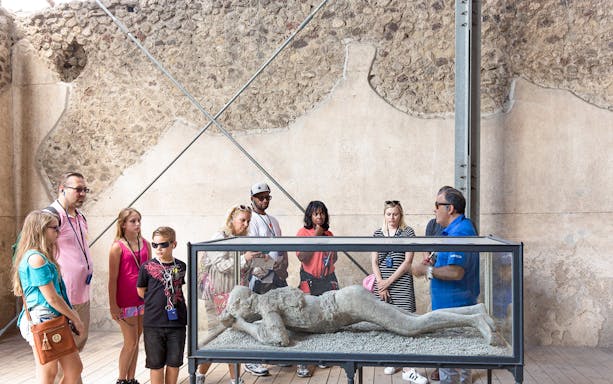 Tour guide explaining Pompeii victim cast to tourists.