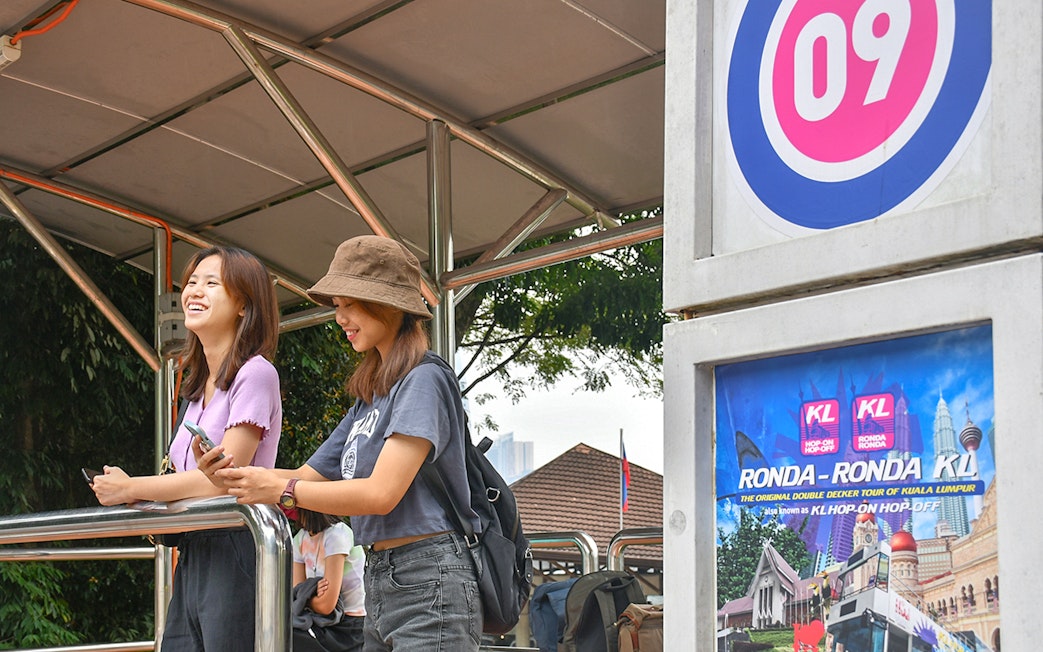 Passengers waiting at a Kuala Lumpur Hop-On Hop-Off tour stop.