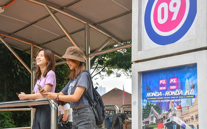 Passengers waiting at a Kuala Lumpur Hop-On Hop-Off tour stop.