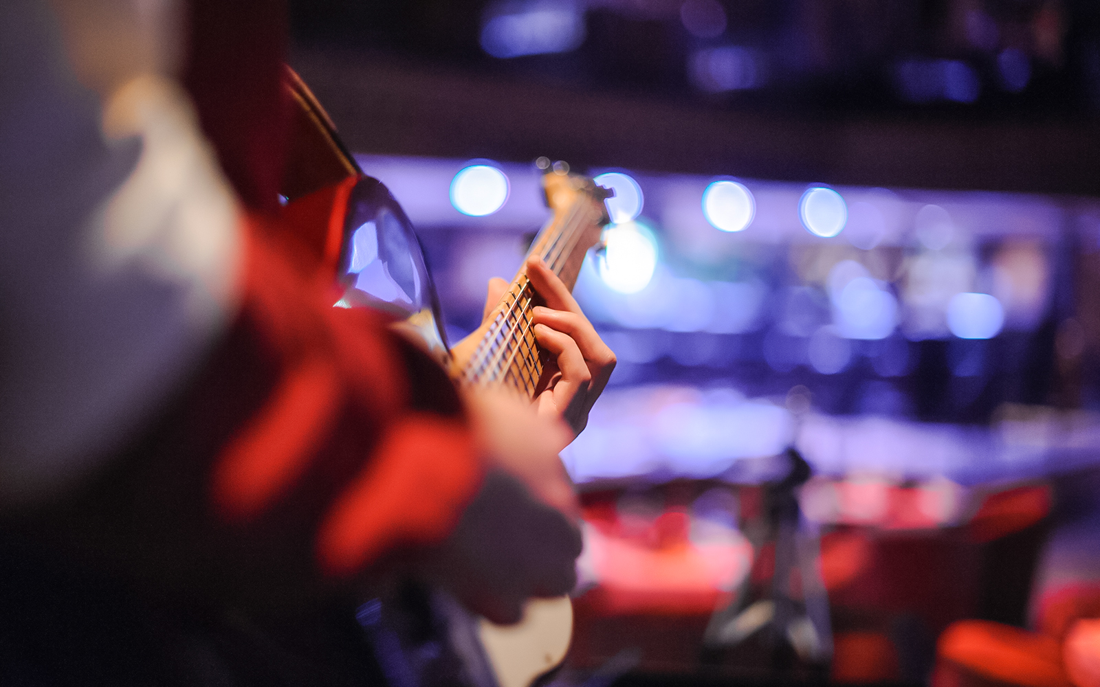 Guitarist performing live music on stage with blurred audience in background.