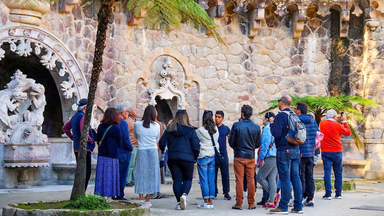 Visitors exploring the ornate stone facade at Quinta da Regaleira in Lisbon, Portugal.