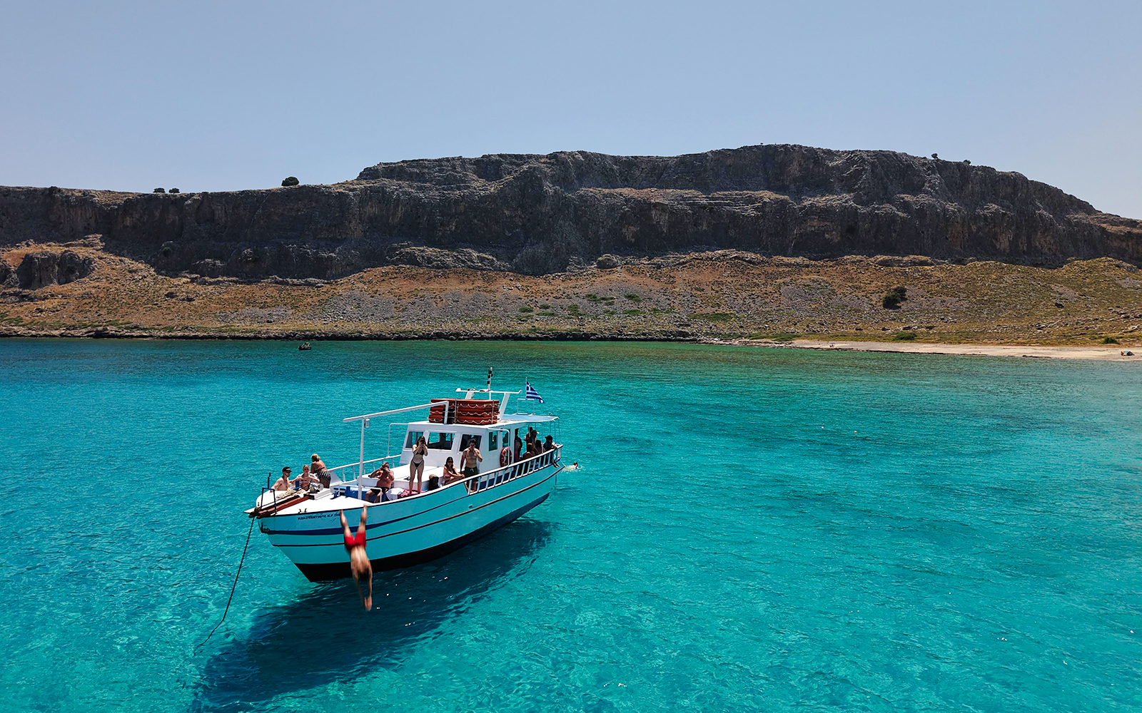 Boat cruise in Lindos with people enjoying turquoise sea water.