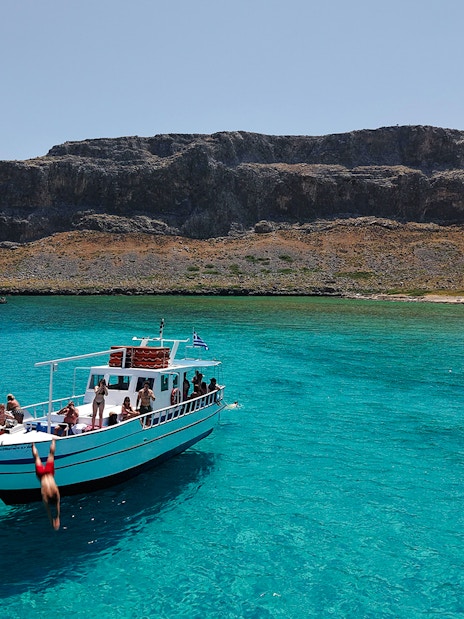 Boat cruise in Lindos with people enjoying turquoise sea water.