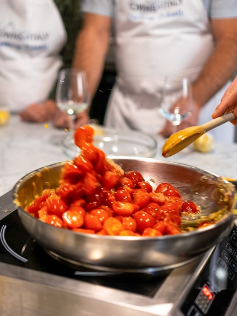 Cooking cherry tomatoes in a pan during a Florence pasta-making class.