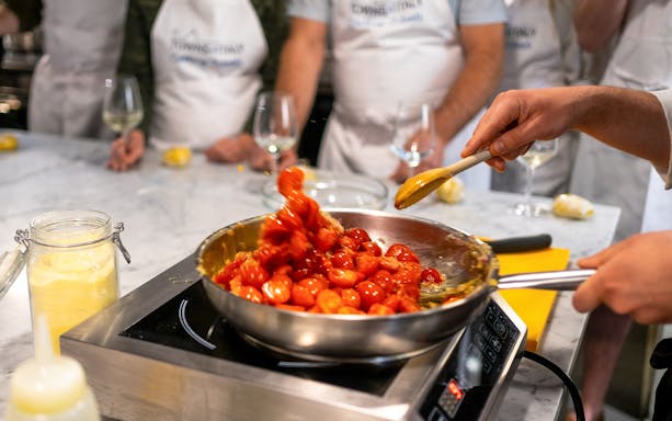 Cooking cherry tomatoes in a pan during a Florence pasta-making class.