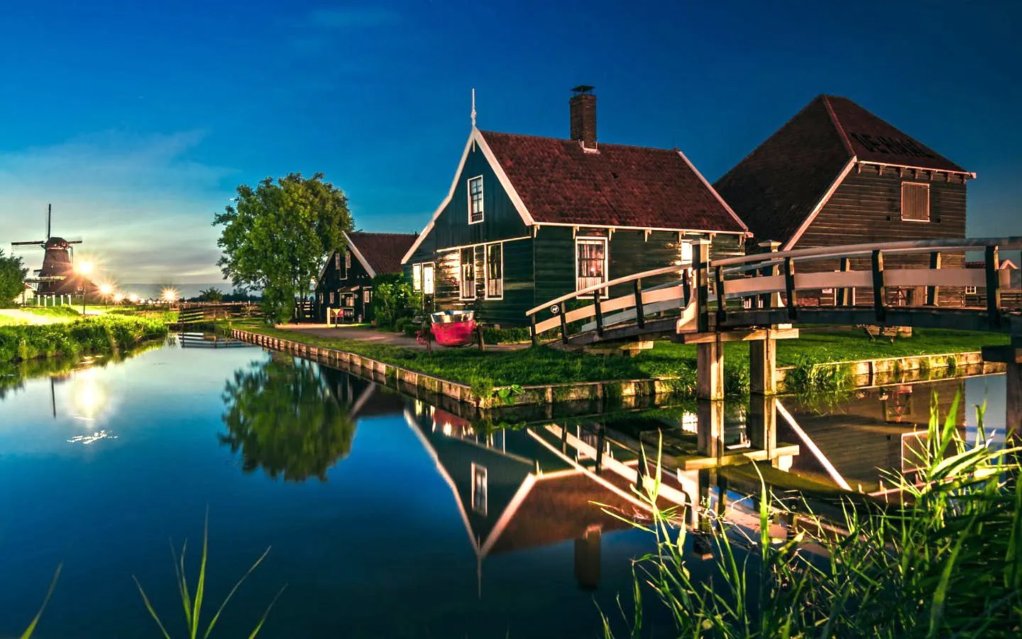 Traditional houses and canal with a bridge in Giethoorn at dusk.
