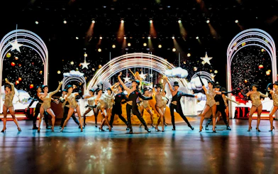 Performers dancing on stage at Friedrichstadt Palast, Berlin, with vibrant lights and costumes.