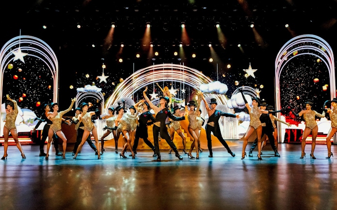 Performers dancing on stage at Friedrichstadt Palast, Berlin, with vibrant lights and costumes.