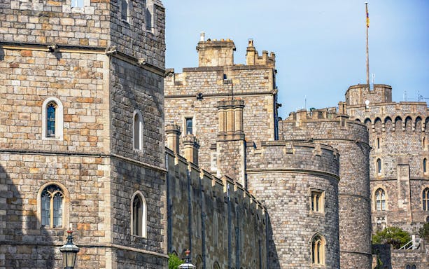 Windsor Castle with red double-decker tour bus in foreground.