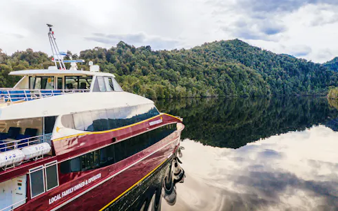 Cruise boat on Gordon River with forested hills in Strahan, Tasmania.