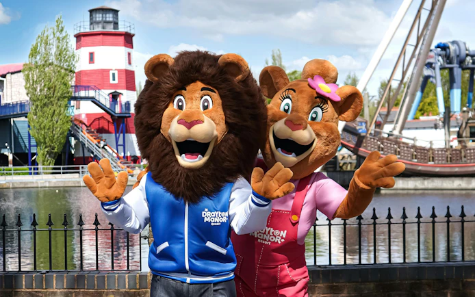 Mascots at Drayton Manor theme park with a lighthouse and ride in the background.
