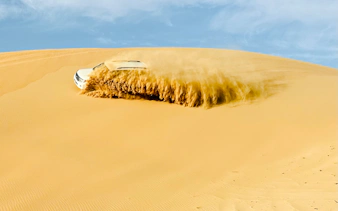 SUV driving through sand dunes during Abu Dhabi desert safari.
