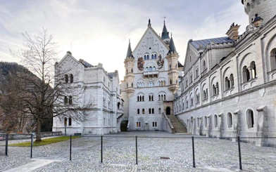 Courtyard view of Neuschwanstein Castle with stone facade and arched windows.