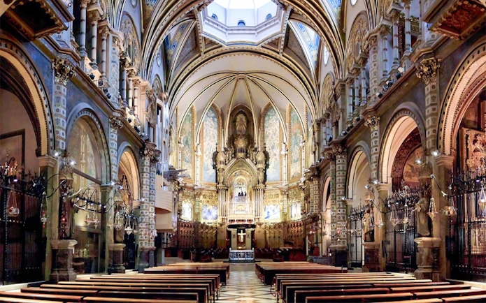 Interior of Santa Maria de Montserrat Abbey with ornate arches and altar.