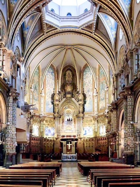 Interior of Santa Maria de Montserrat Abbey with ornate arches and altar.