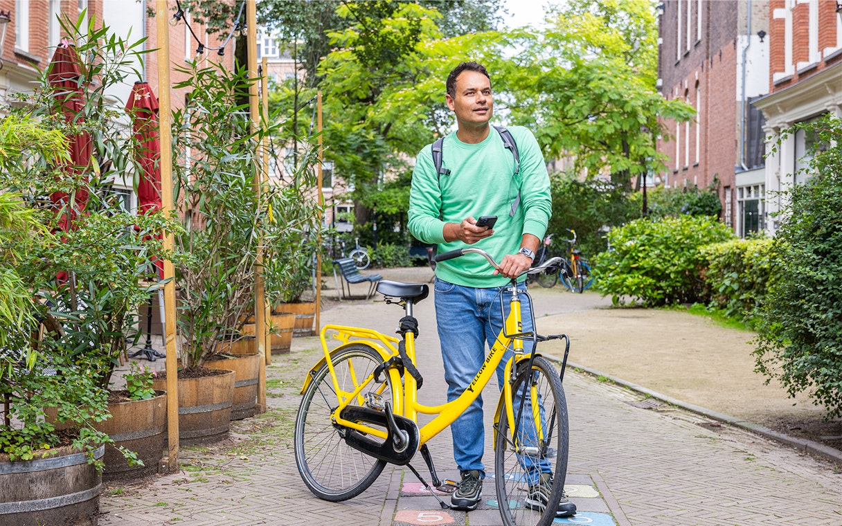 Man with yellow bike exploring Amsterdam street using I amsterdam City Card.