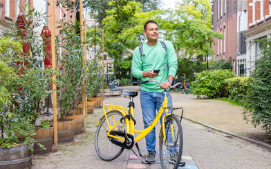 Man with yellow bike exploring Amsterdam street using I amsterdam City Card.