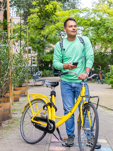 Man with yellow bike exploring Amsterdam street using I amsterdam City Card.