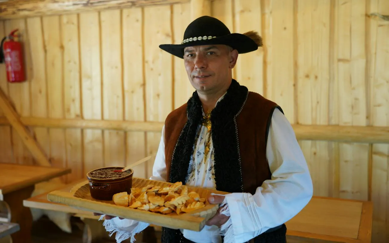 Traditional Polish meal served by a man in regional attire in Zakopane.