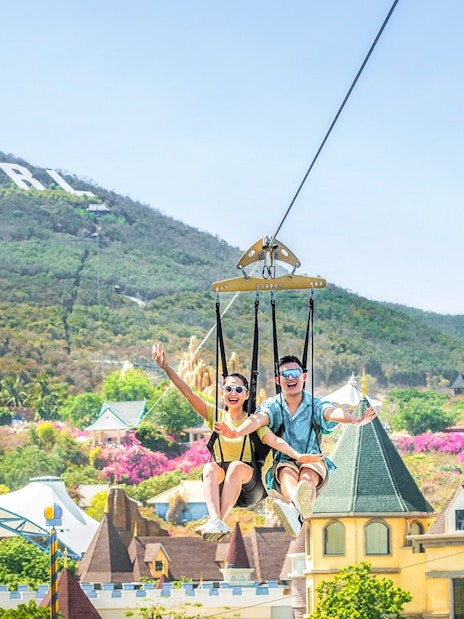 Ziplining at VinWonders with castle backdrop and Vinpearl sign on hill.