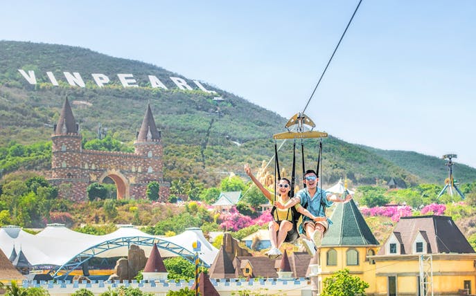 Ziplining at VinWonders with castle backdrop and Vinpearl sign on hill.
