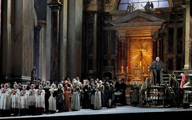 Opera performance of Tosca with a choir and priest in a grand cathedral setting.