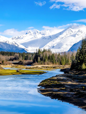 Mendenhall River flowing with snow-capped Mendenhall Glacier in Juneau, Alaska.