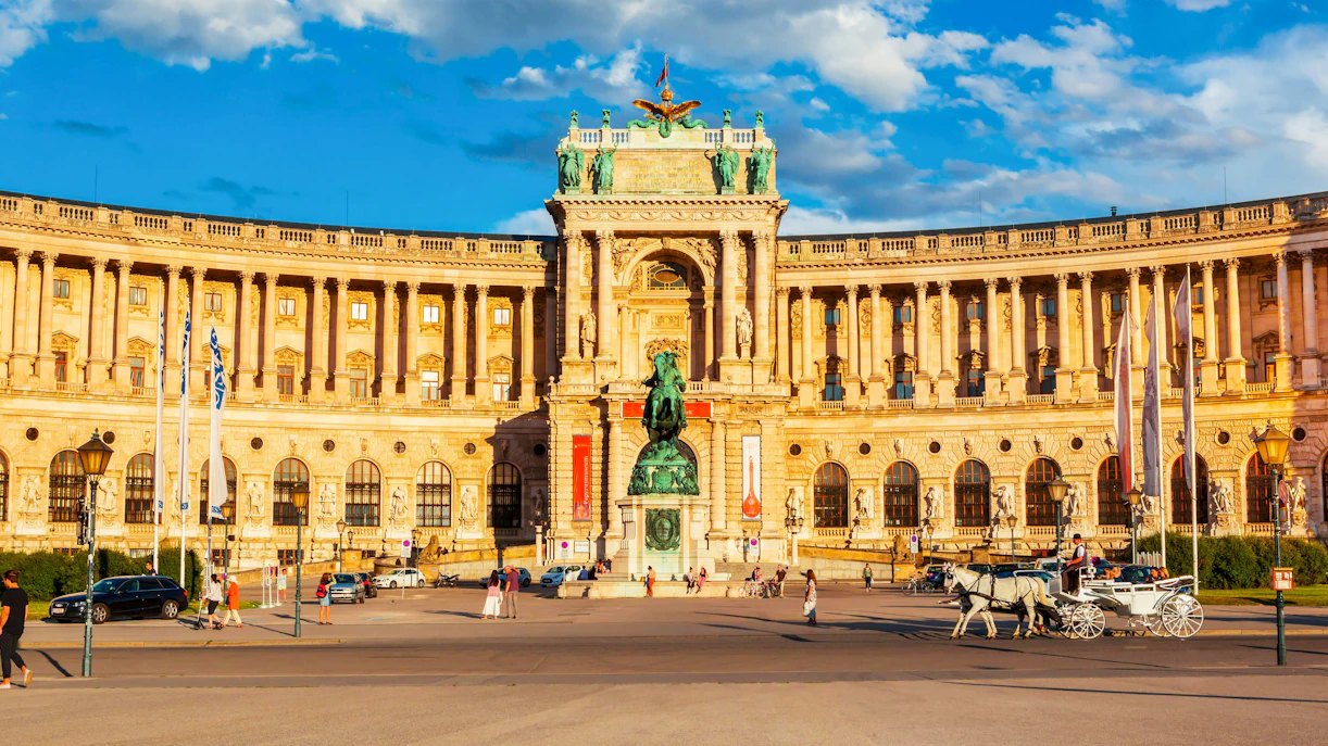 Austrian National Library at Hofburg Complex, Vienna, with horse-drawn carriage in foreground.