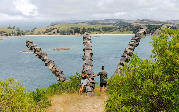 Visitors admire rock formations overlooking the sea on Auckland's Tikapa Moana cruise.