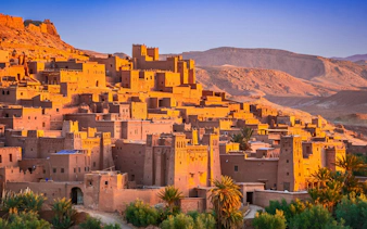 Ait Ben-Haddou kasbah with sunlit clay buildings in Morocco's desert landscape.