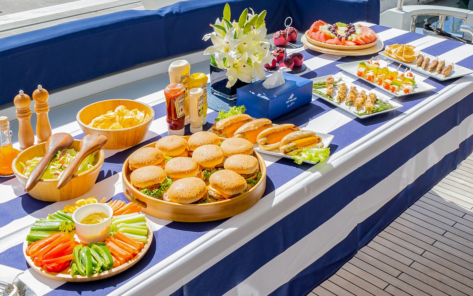 BBQ lunch spread on a yacht in Dubai with burgers, hot dogs, and salads.