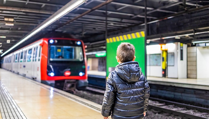 Child holding Barcelona Travel Card with cityscape in the background.