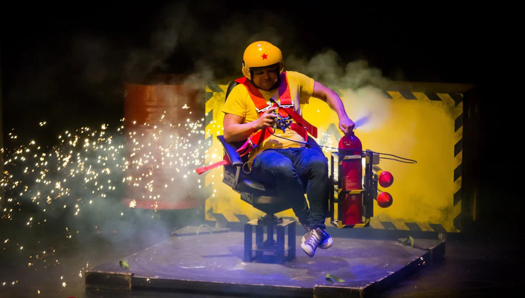 Performer in safety gear with fire extinguisher on stage at Brainiac Live Westend.