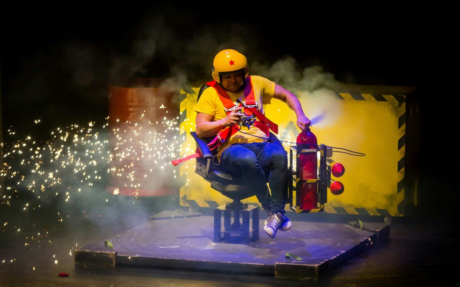 Performer in safety gear with fire extinguisher on stage at Brainiac Live Westend.