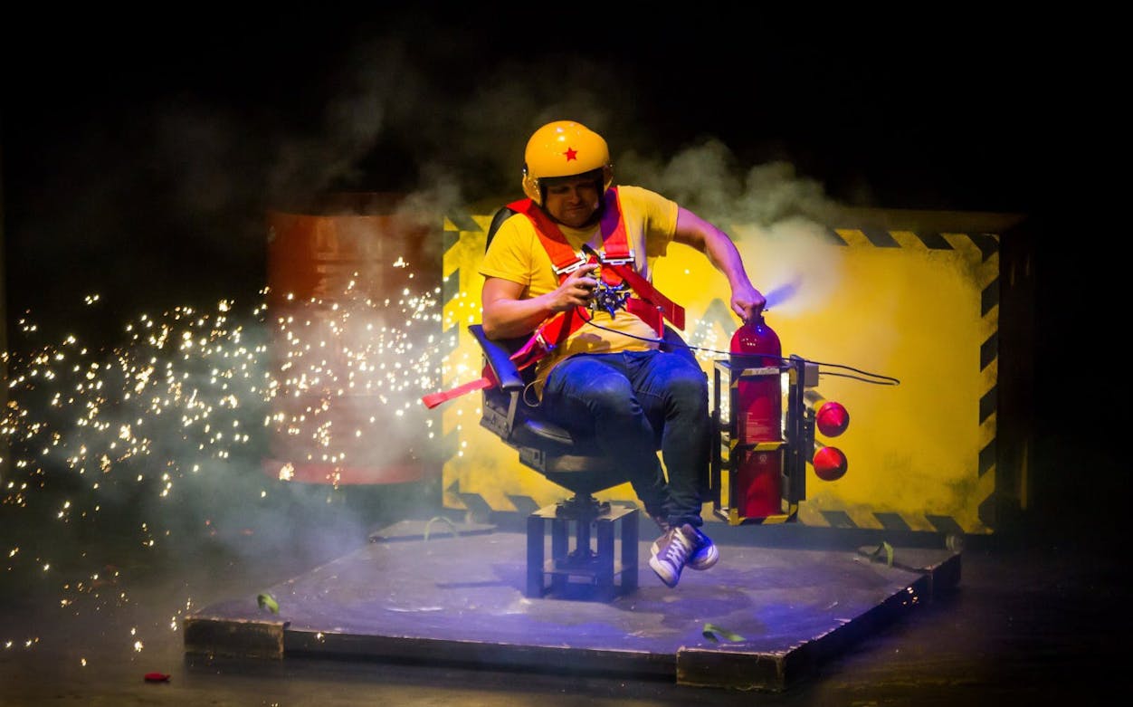 Performer in safety gear with fire extinguisher on stage at Brainiac Live Westend.
