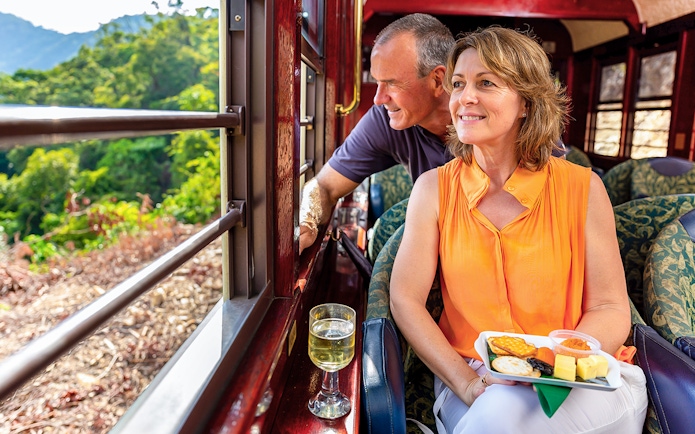 Kuranda Railway Gold Class passengers enjoying scenic view and refreshments, Cairns.