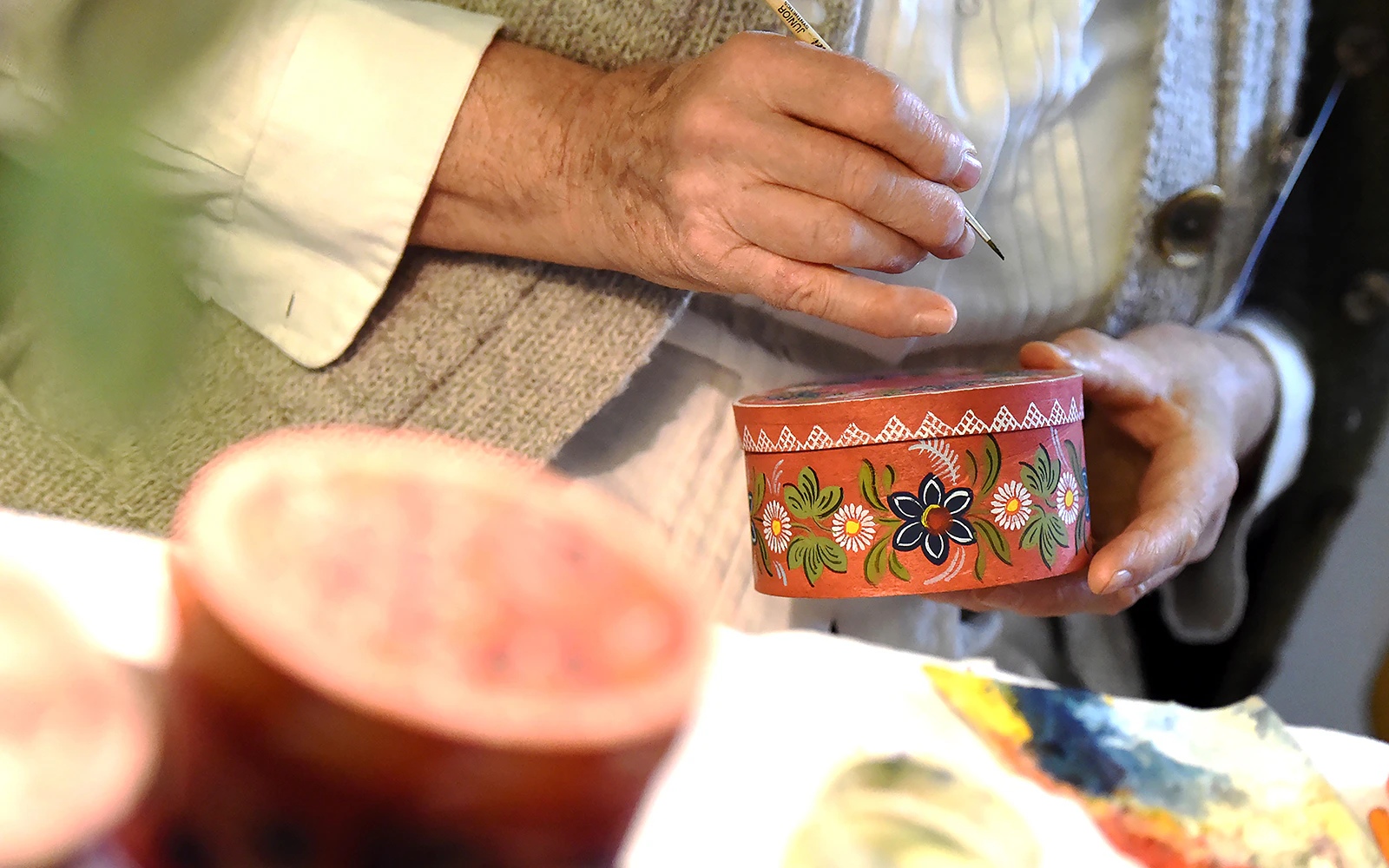 Hand painting traditional floral designs on a wooden box in Norway.