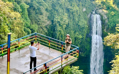 Visitors on a viewing platform near a waterfall in Bandung, Indonesia.