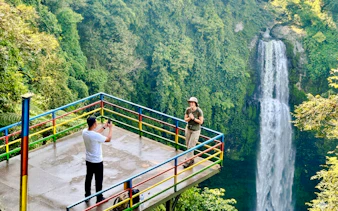 Visitors on a viewing platform near a waterfall in Bandung, Indonesia.