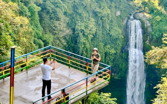 Visitors on a viewing platform near a waterfall in Bandung, Indonesia.