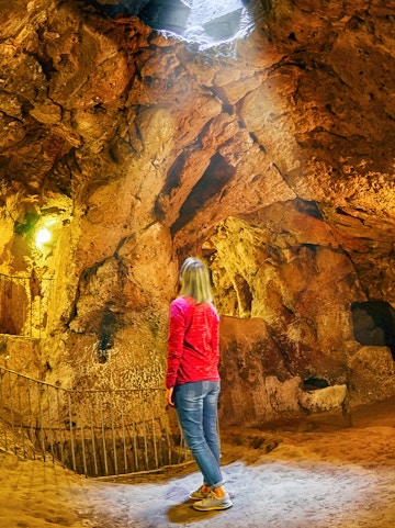 Visitor exploring Ozkonak Underground City cave formations in Cappadocia, Turkey.