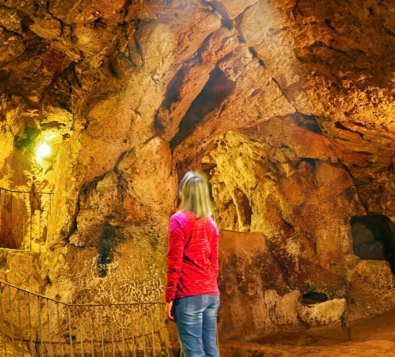 Visitor exploring Ozkonak Underground City cave formations in Cappadocia, Turkey.
