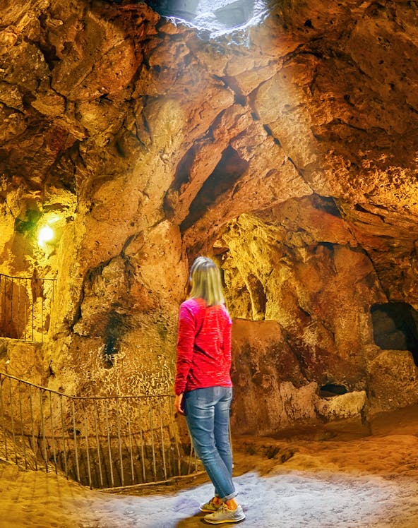 Visitor exploring Ozkonak Underground City cave formations in Cappadocia, Turkey.