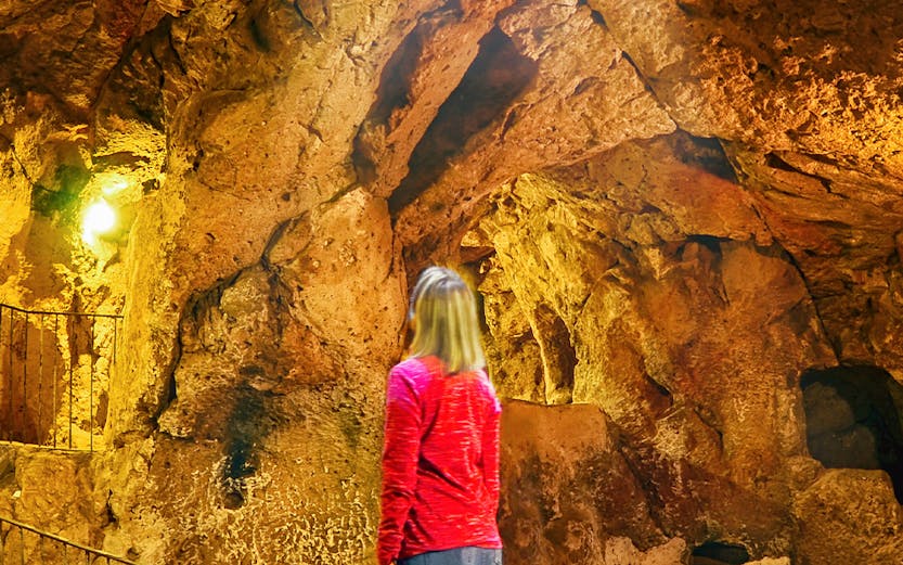 Visitor exploring Ozkonak Underground City cave formations in Cappadocia, Turkey.