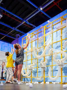 Children interacting with a tube wall exhibit at Chaos Lab, Singapore.