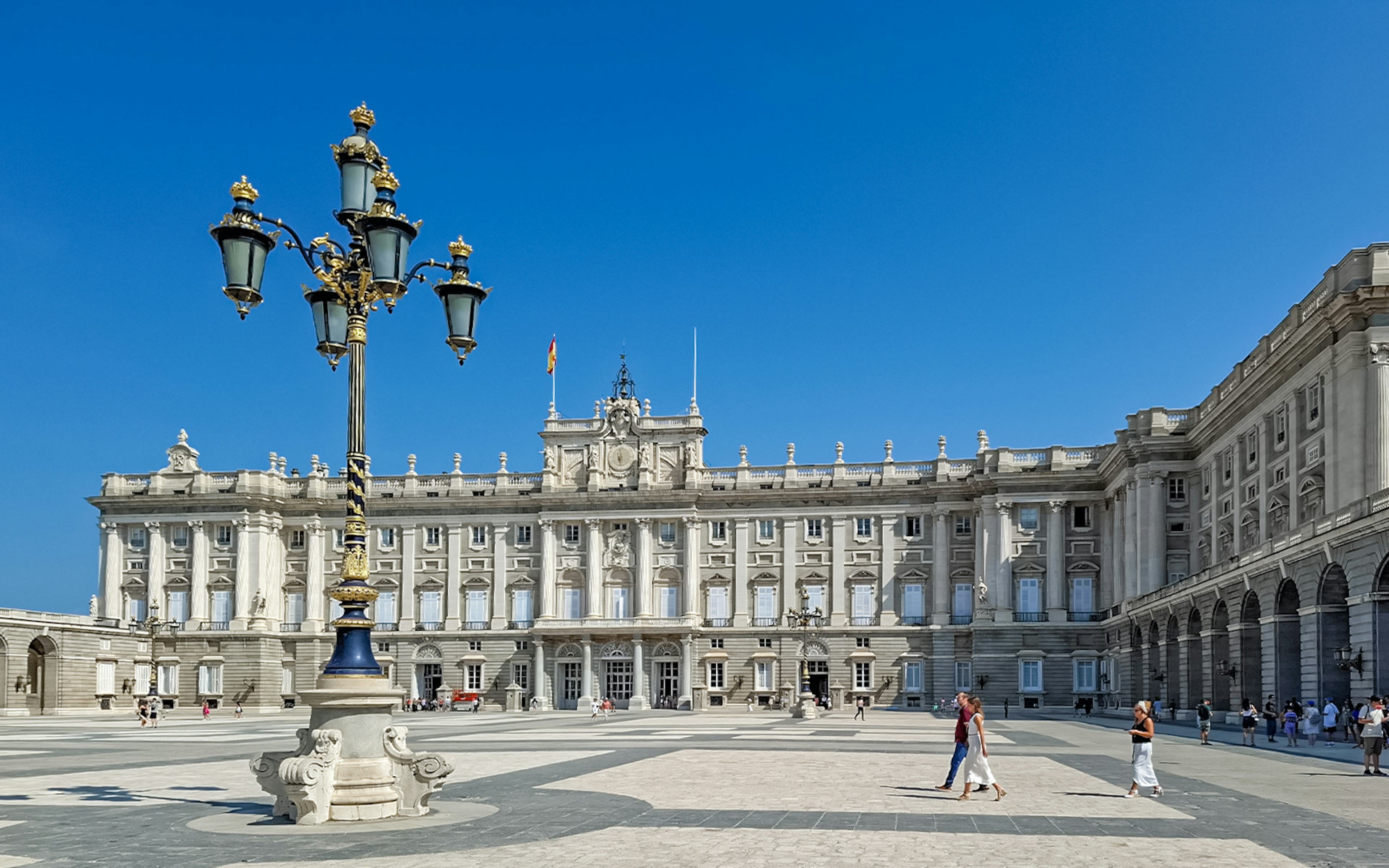 Royal Palace of Madrid courtyard with visitors walking, Spain.